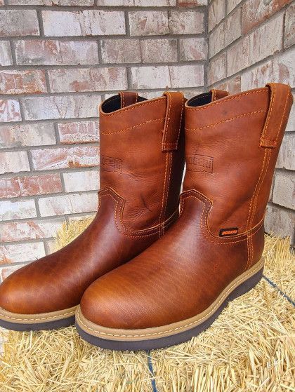 A pair of brown leather boots are sitting on top of a pile of hay.