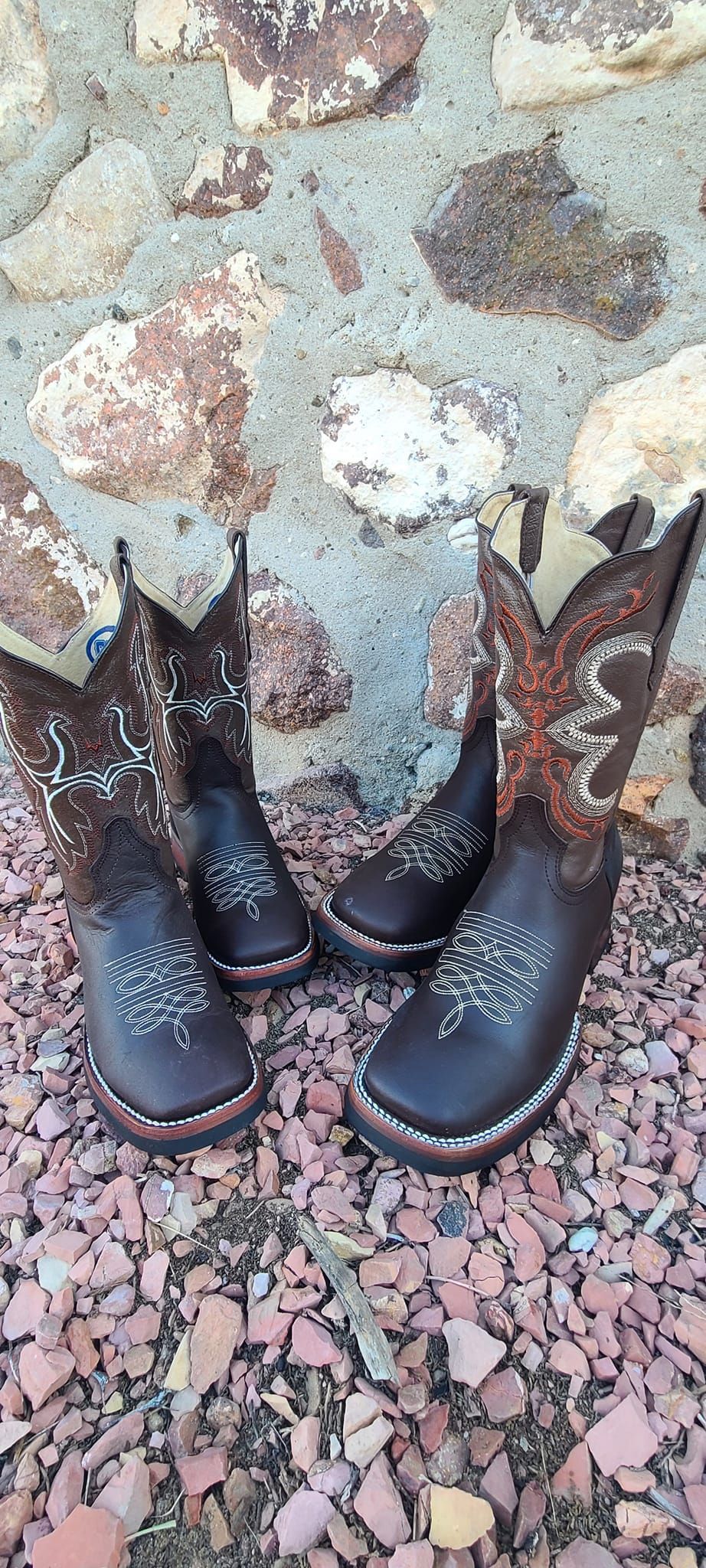 A pair of cowboy boots sitting on top of a pile of rocks.