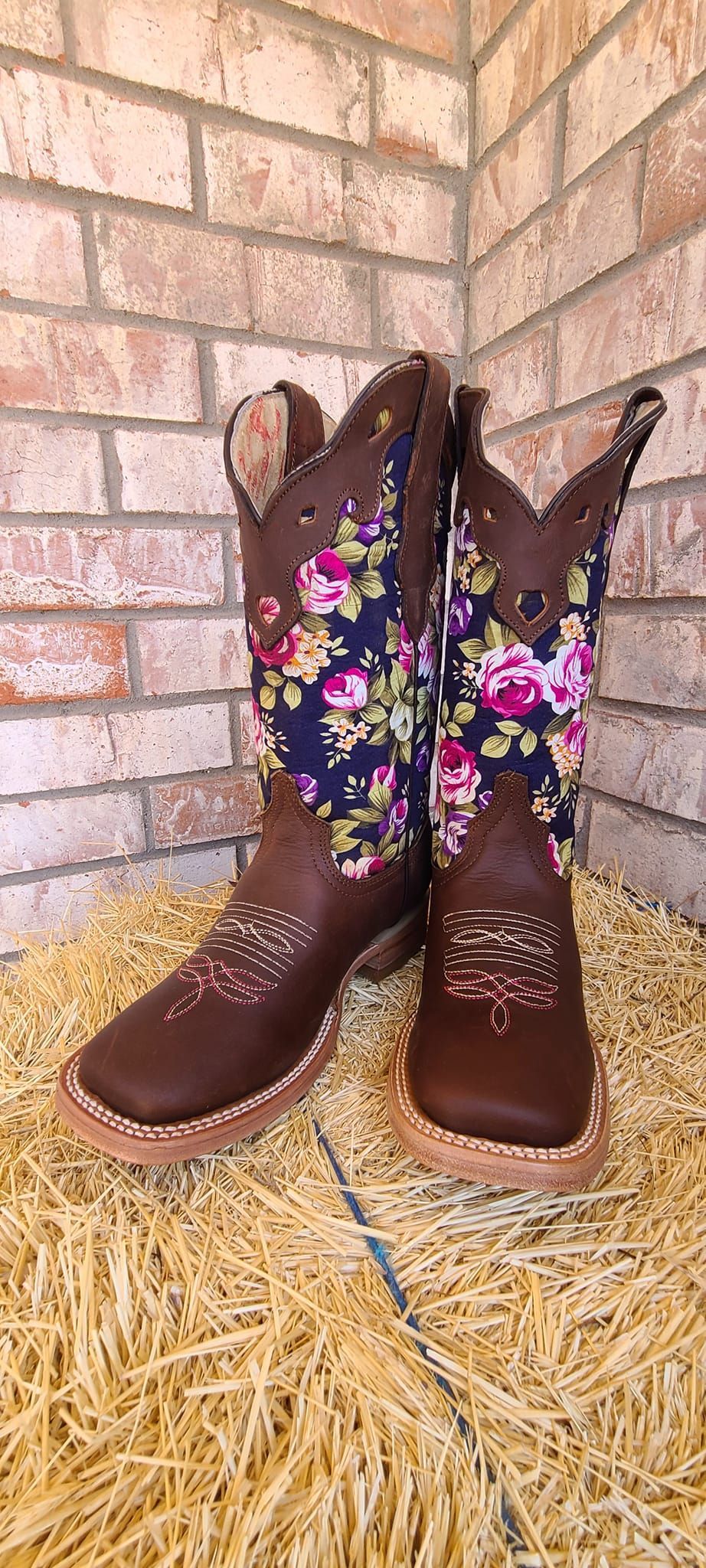 A pair of cowboy boots are sitting on top of a pile of hay.