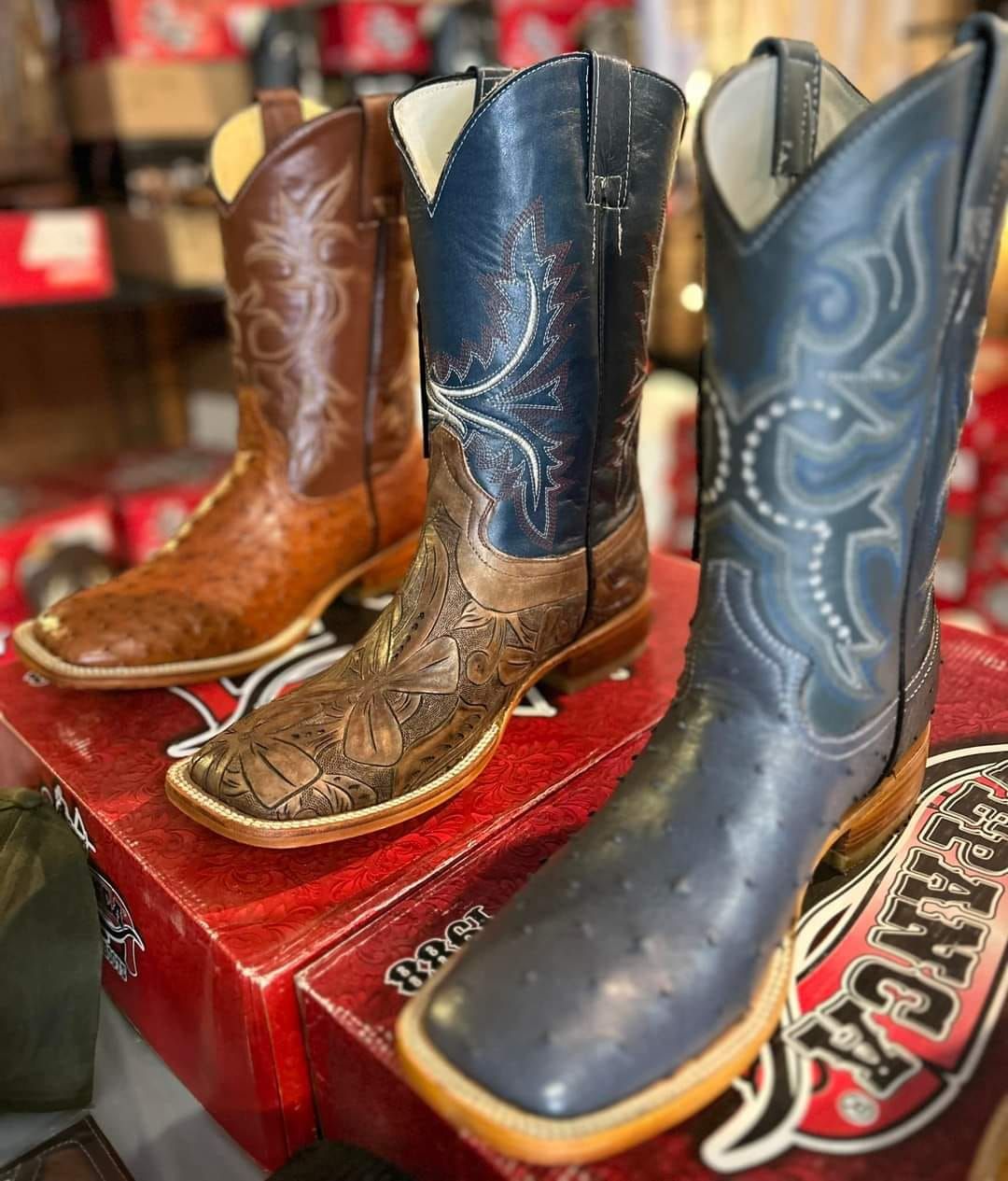 Three pairs of cowboy boots are sitting on top of a red box.