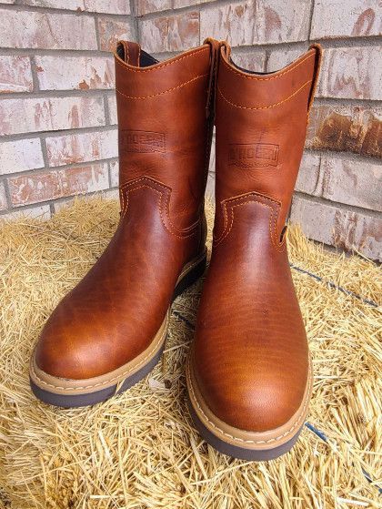A pair of brown leather boots are sitting on a pile of hay.