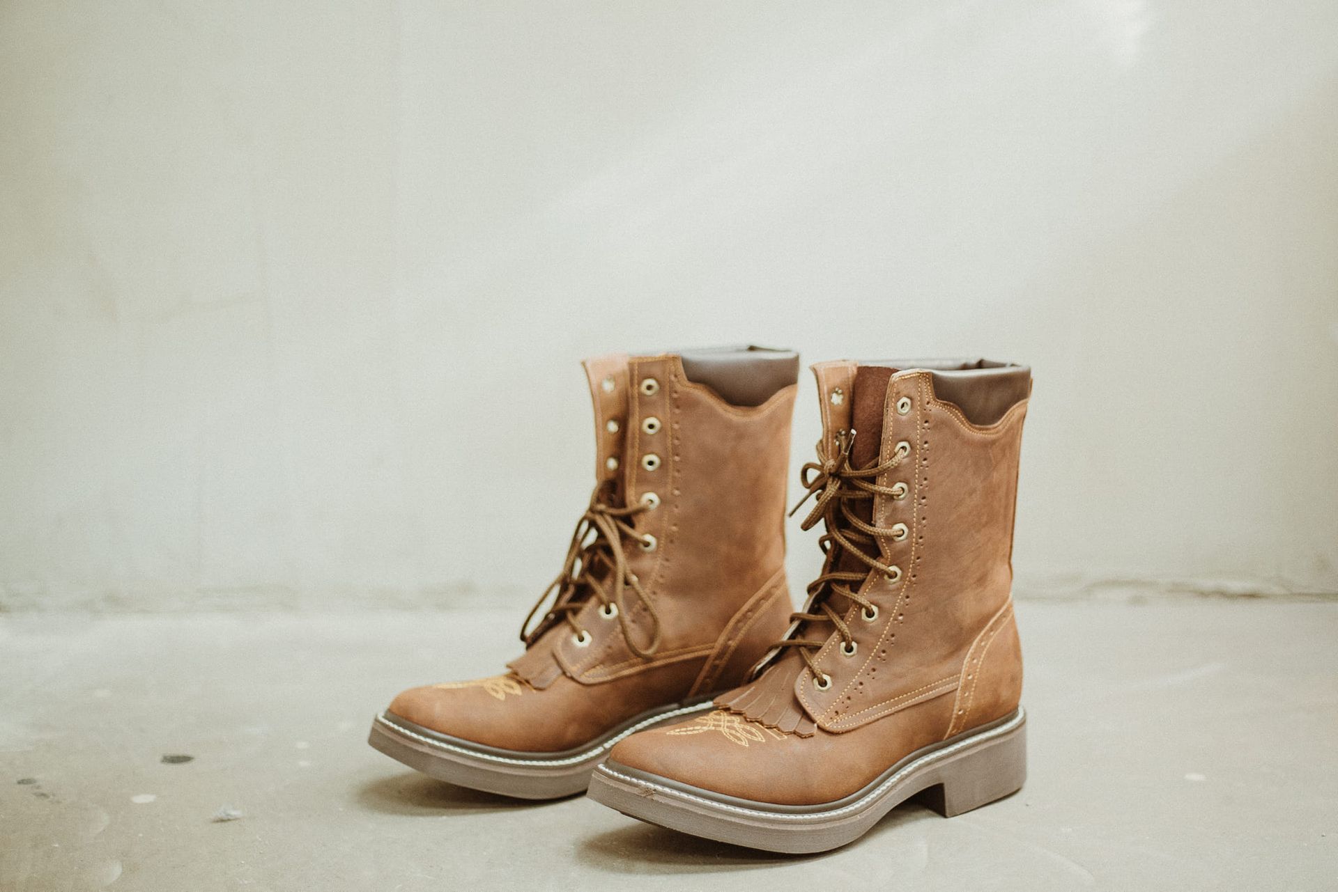 A pair of brown boots are sitting on a concrete floor.
