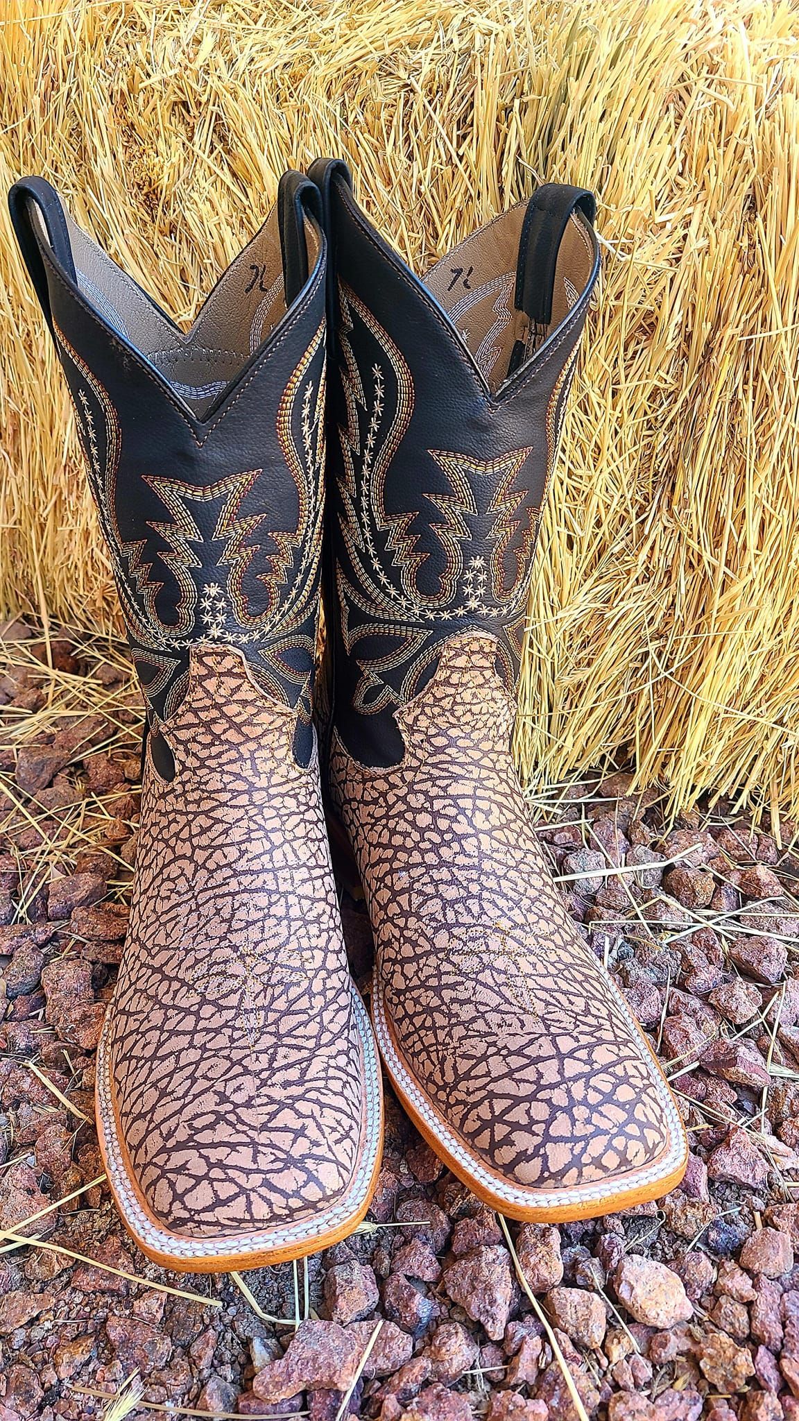 A pair of cowboy boots are sitting on top of a pile of rocks.