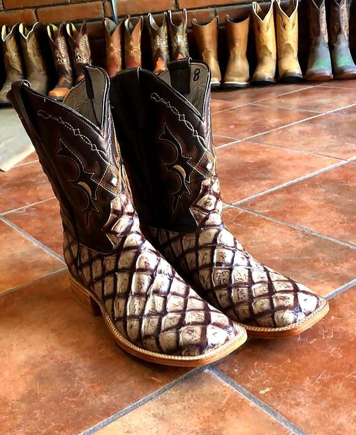 A pair of cowboy boots are sitting on a tiled floor.