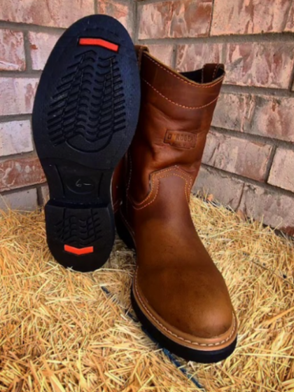 A pair of brown boots sitting on top of a pile of hay