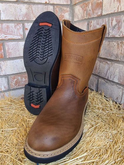 A pair of brown boots are sitting on top of a pile of hay.