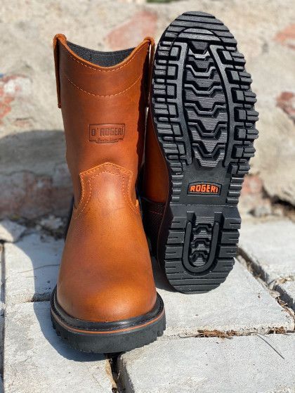 A pair of brown boots are sitting on a brick sidewalk.