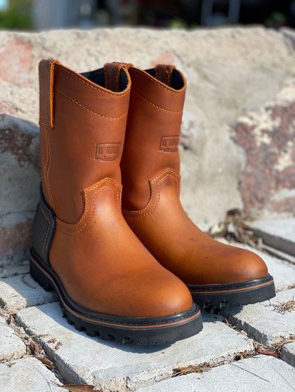 A pair of brown boots are sitting on top of a brick wall.