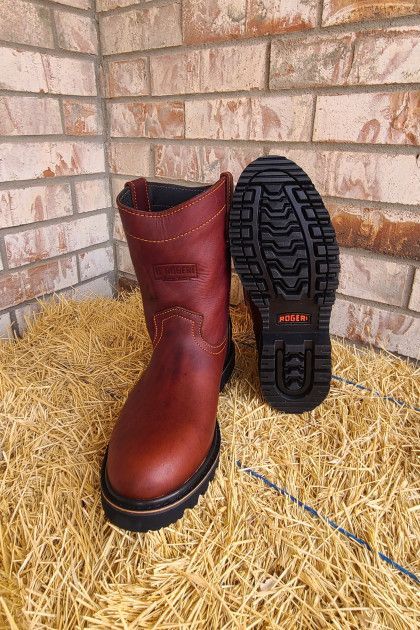 A pair of red boots sitting on top of a pile of hay.