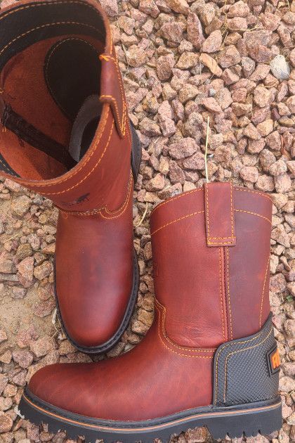 A pair of brown leather boots are sitting on a pile of rocks.