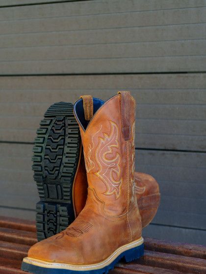 A pair of brown cowboy boots sitting on a wooden bench