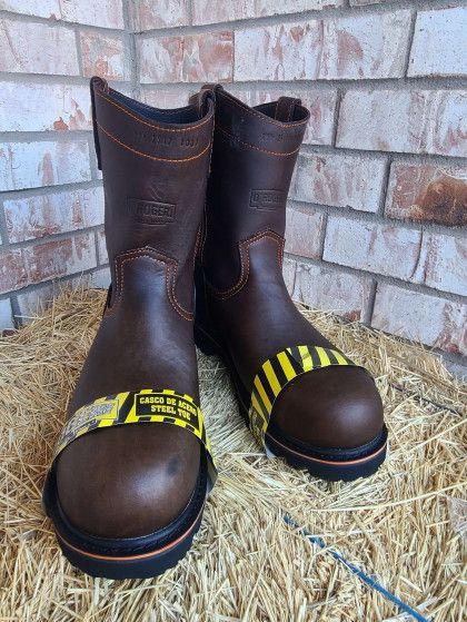 A pair of brown boots are sitting on top of a pile of hay.