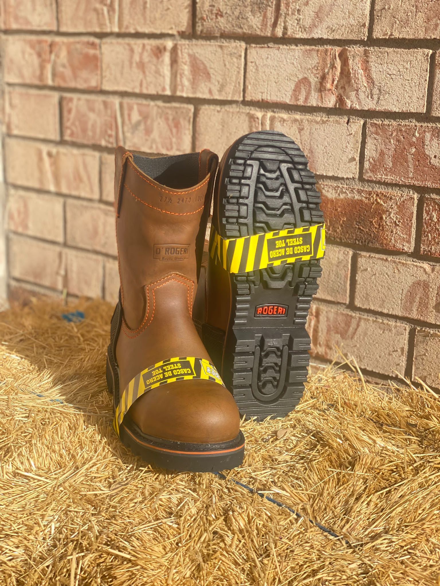 A pair of brown boots are sitting on top of a pile of hay.