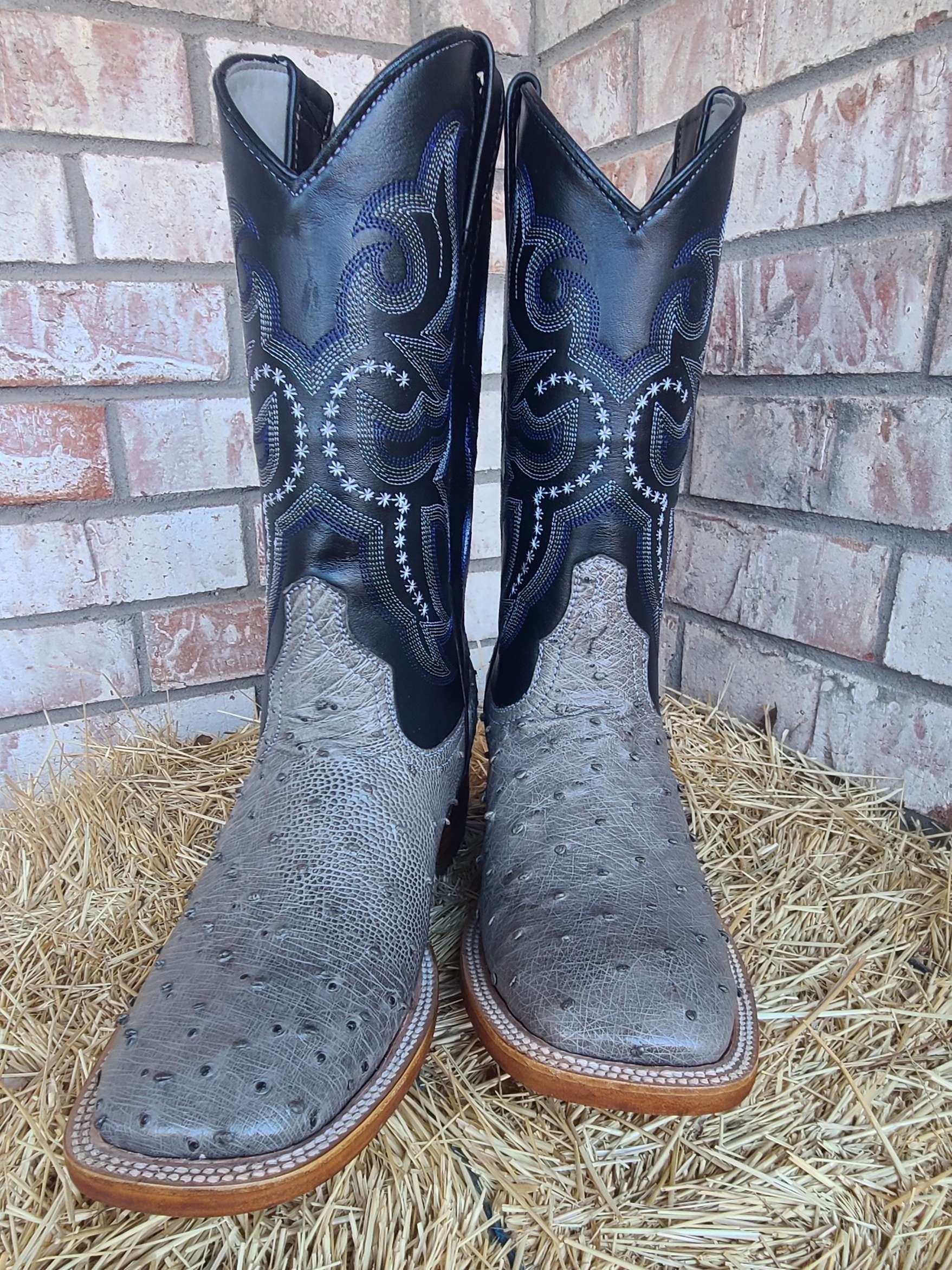 A pair of cowboy boots are sitting on top of a pile of hay.