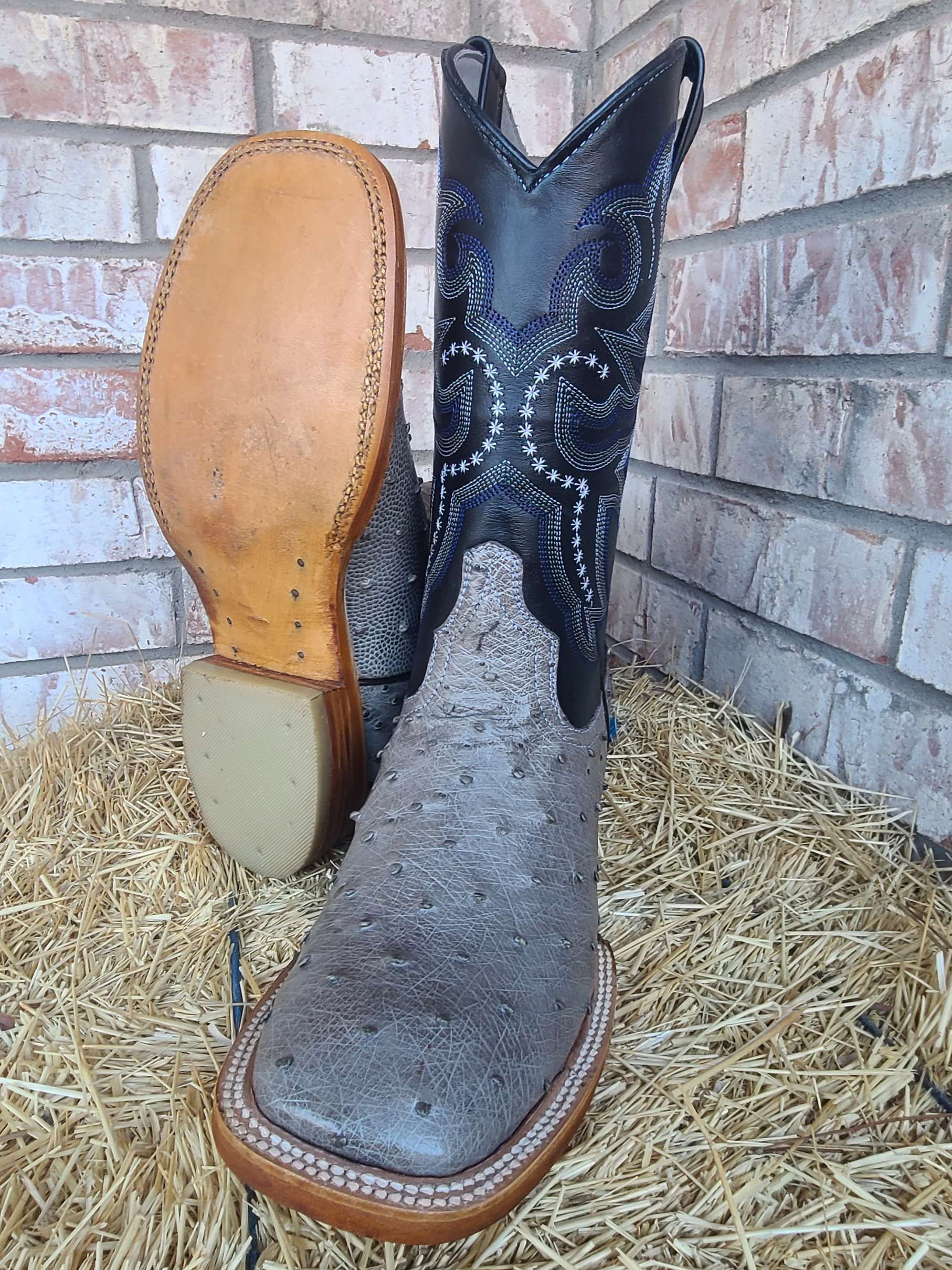 A pair of cowboy boots are sitting on top of a pile of hay.
