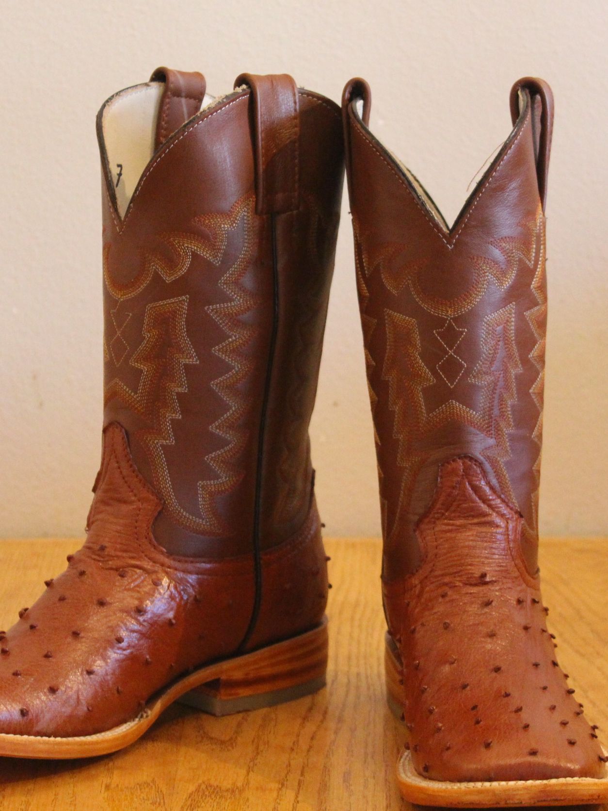 A pair of brown cowboy boots are sitting on a wooden table