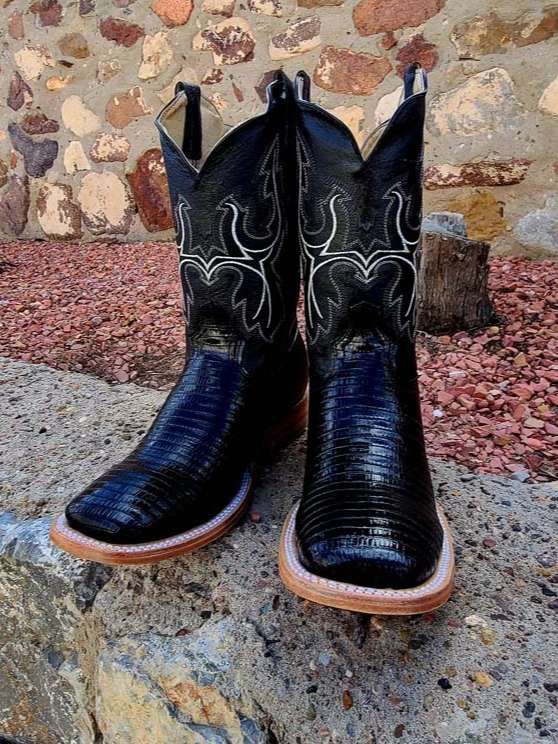 A pair of black cowboy boots are sitting on top of a rock.