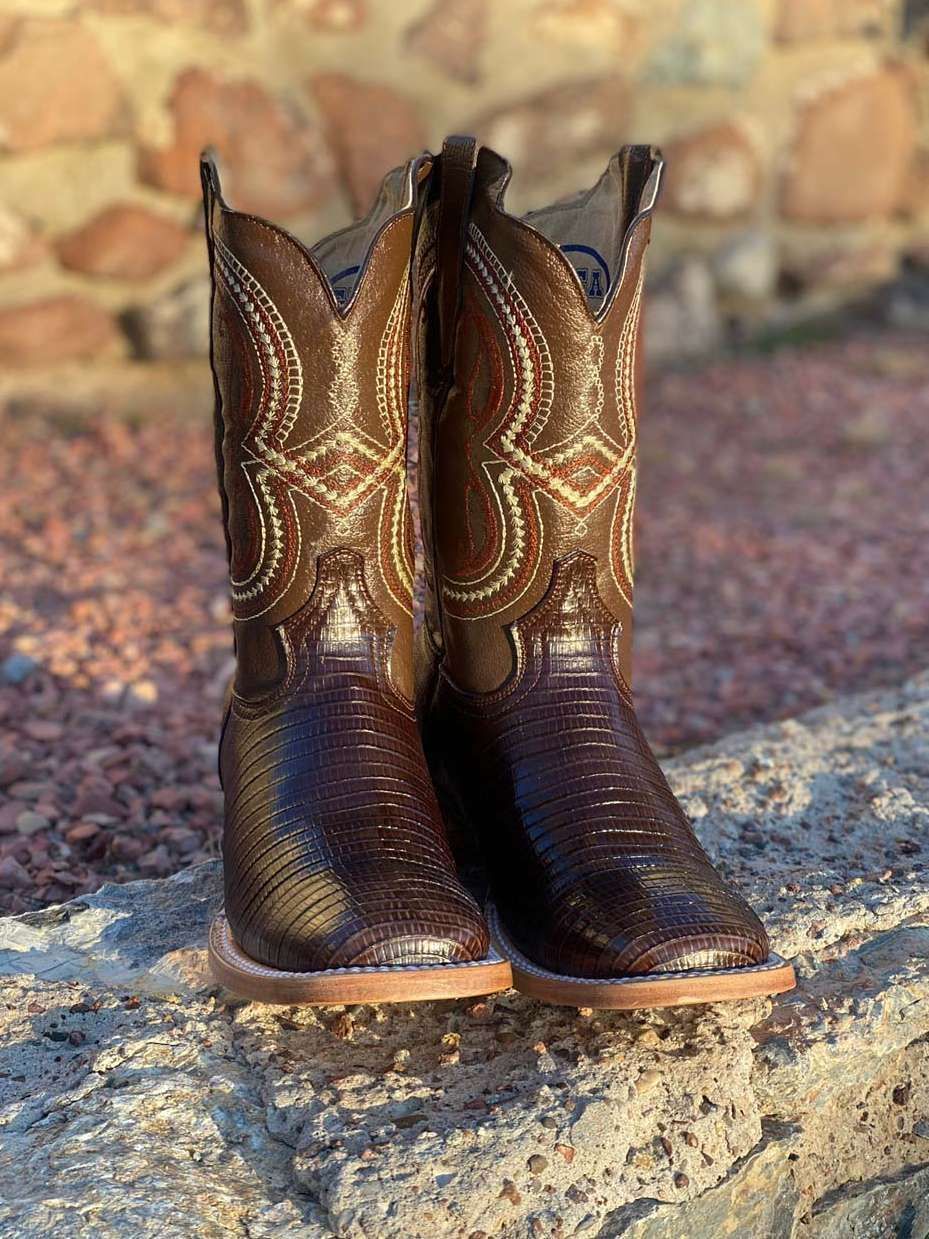 A pair of brown cowboy boots are sitting on top of a rock.