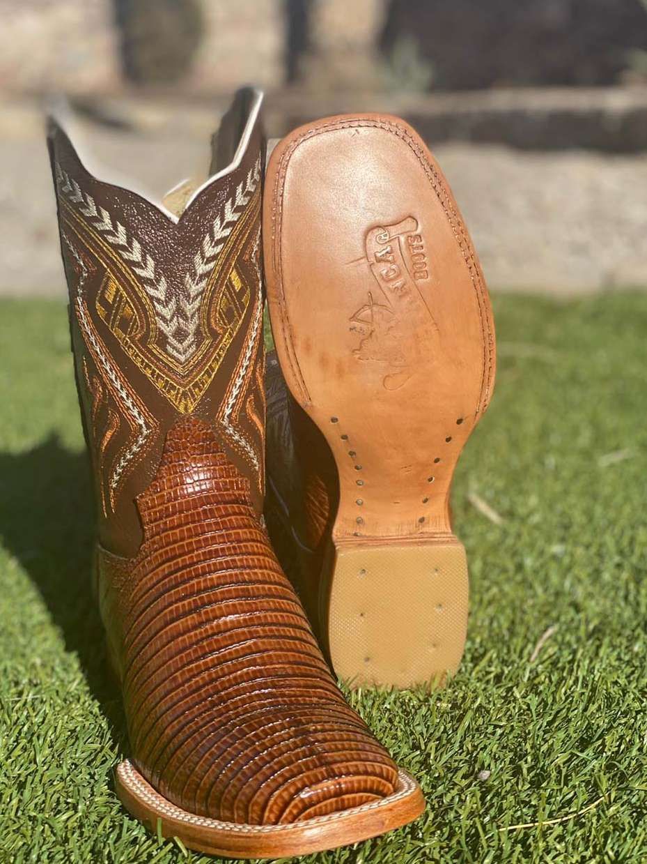 A pair of brown cowboy boots are sitting on top of a lush green field.