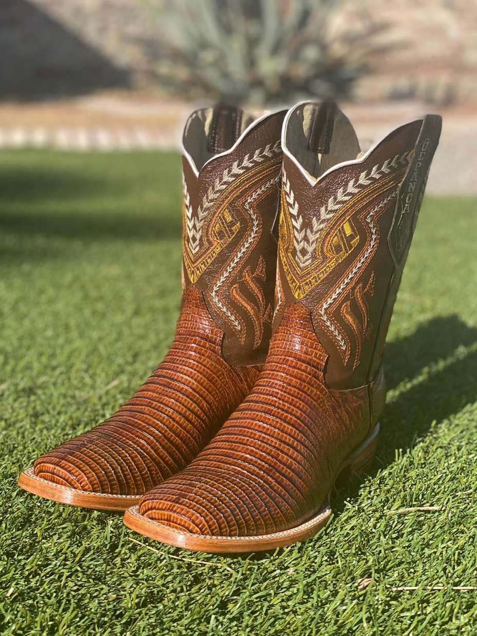 A pair of brown cowboy boots are sitting on top of a lush green field.