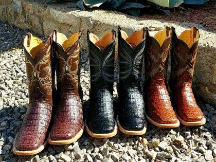 A row of cowboy boots sitting on top of a pile of gravel.