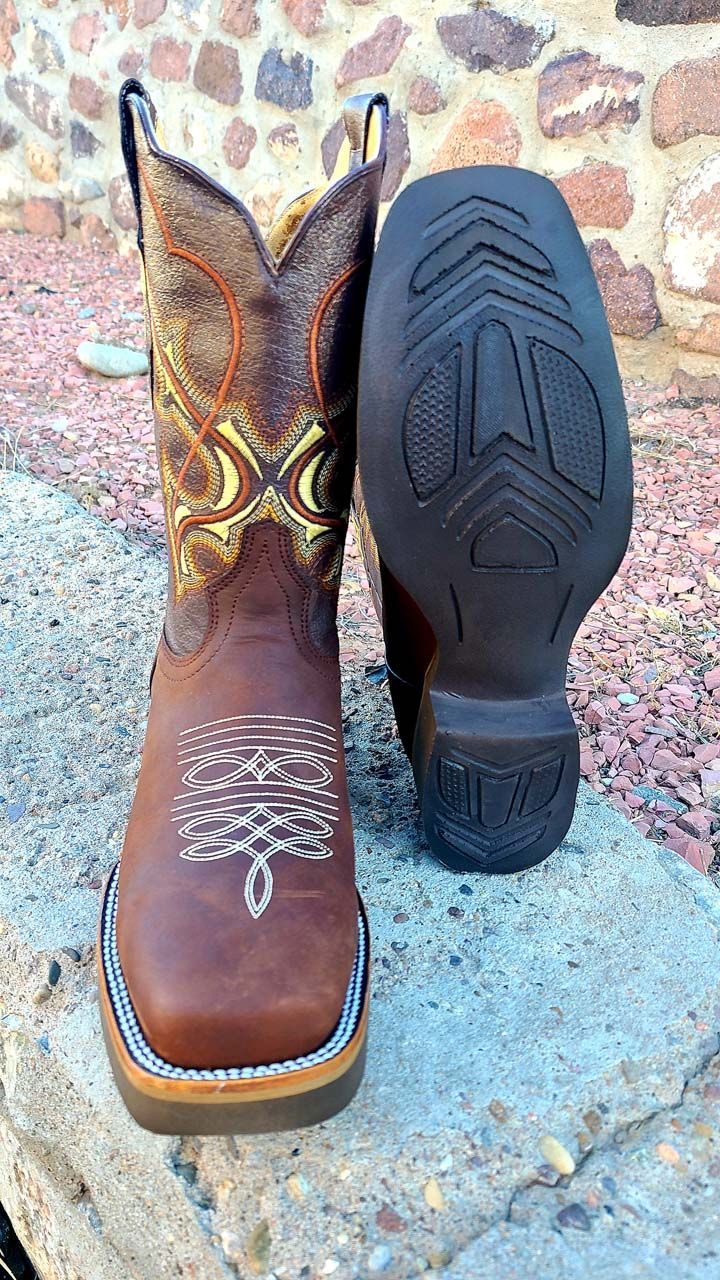 A pair of brown cowboy boots are sitting on top of a rock.