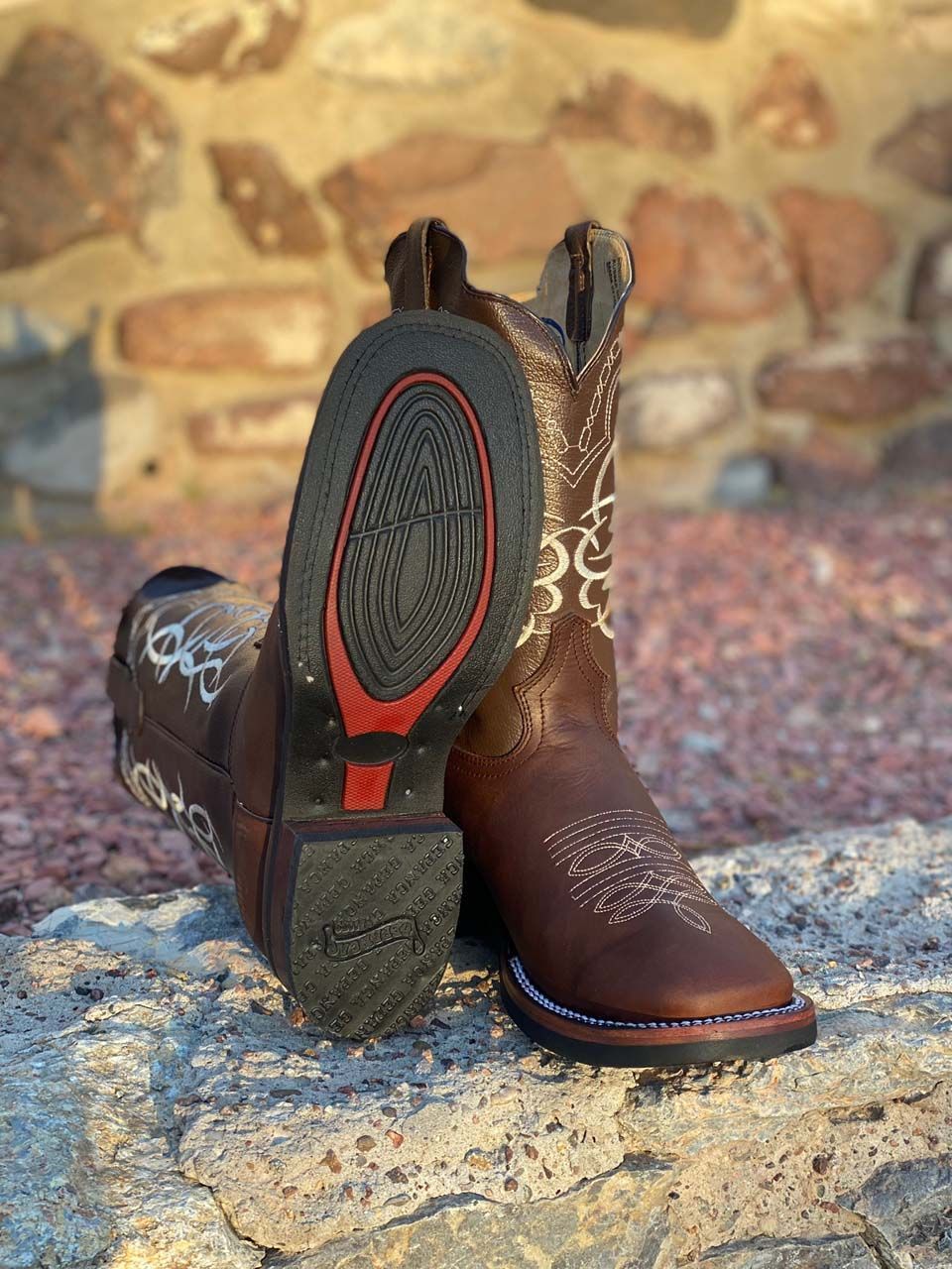 A pair of brown cowboy boots are sitting on top of a rock.