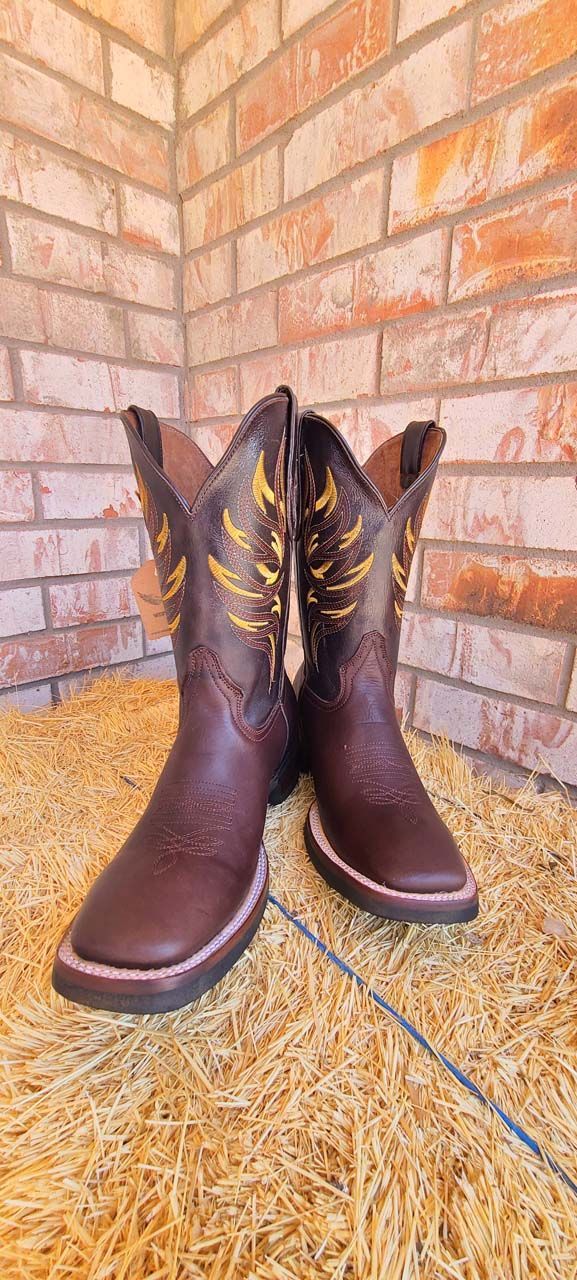 A pair of brown cowboy boots are sitting on top of a pile of hay.