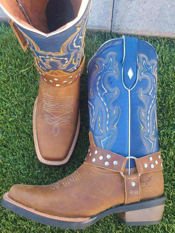A pair of brown and blue cowboy boots are sitting on the grass.