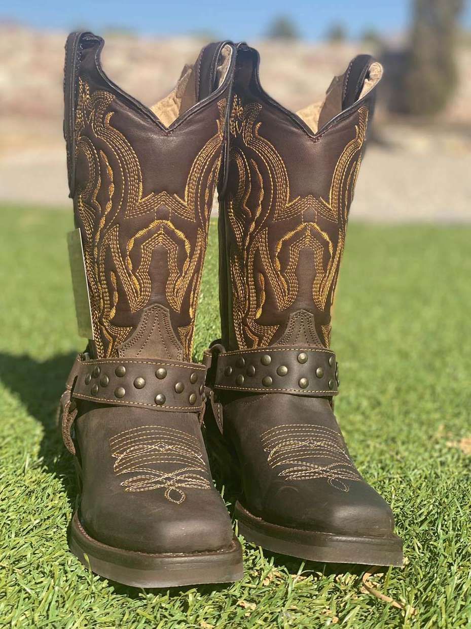 A pair of brown cowboy boots are sitting on top of a lush green field.