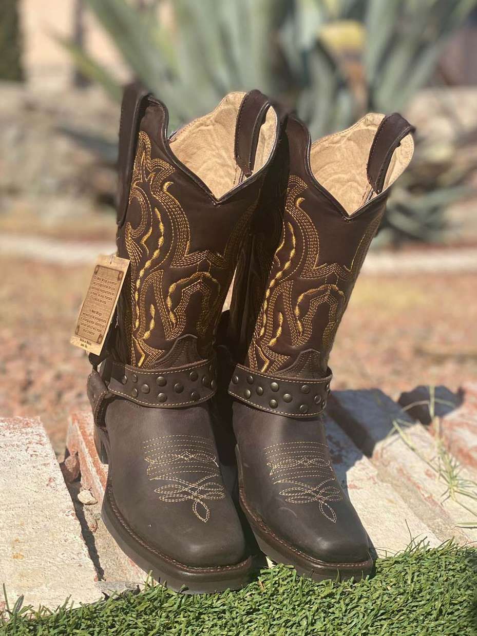 A pair of brown cowboy boots are sitting on top of a rock.