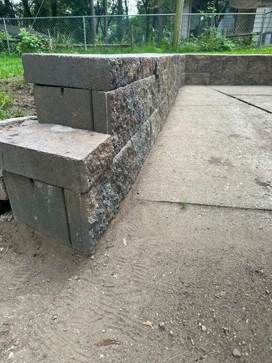 A stone wall is sitting next to a concrete walkway.
