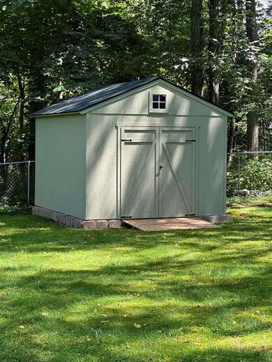 A small shed is sitting in the middle of a lush green field.