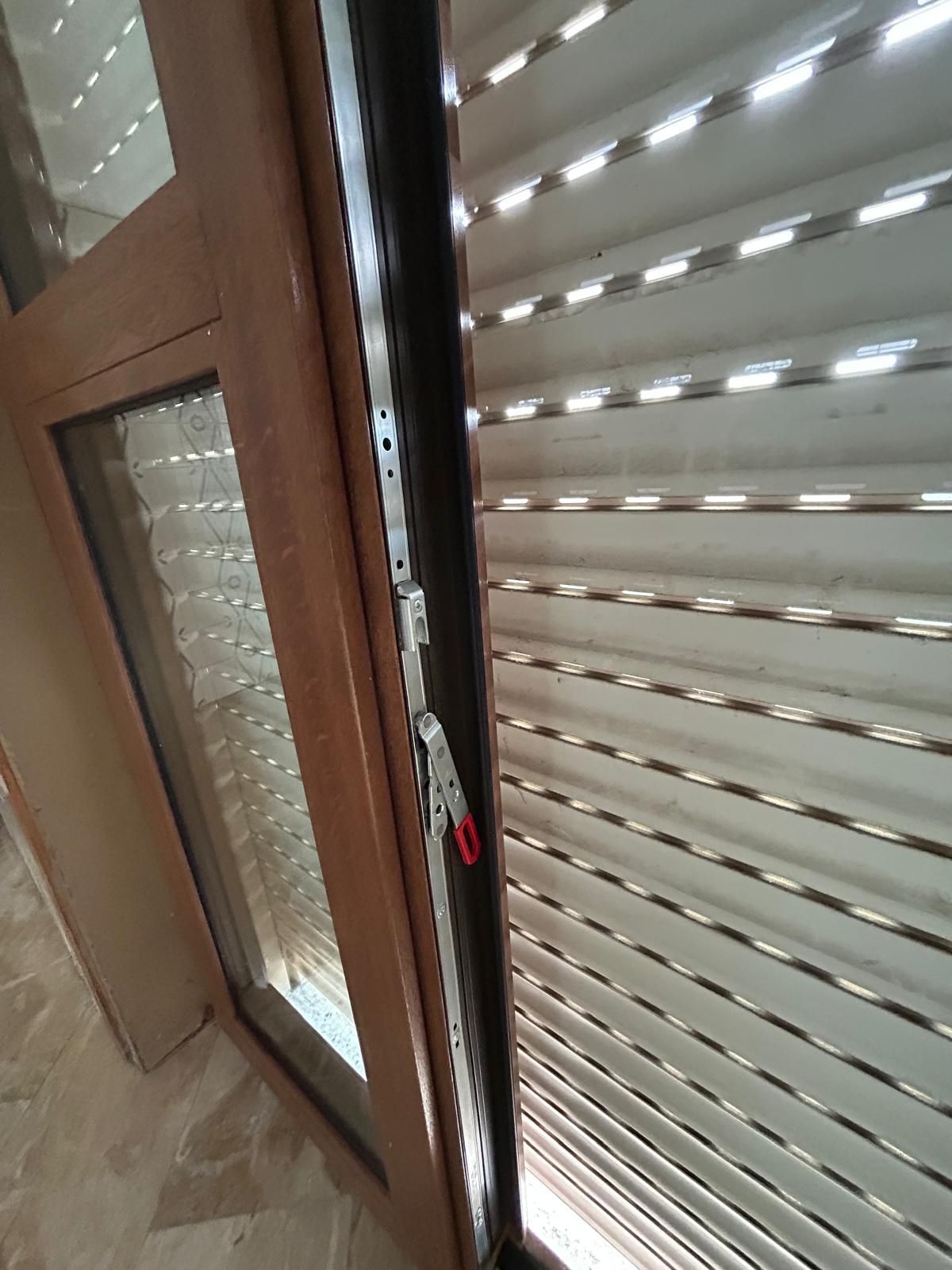 Porte in legno aperte che conducono a un balcone con vista sulla città; corridoio con pavimento in marmo.