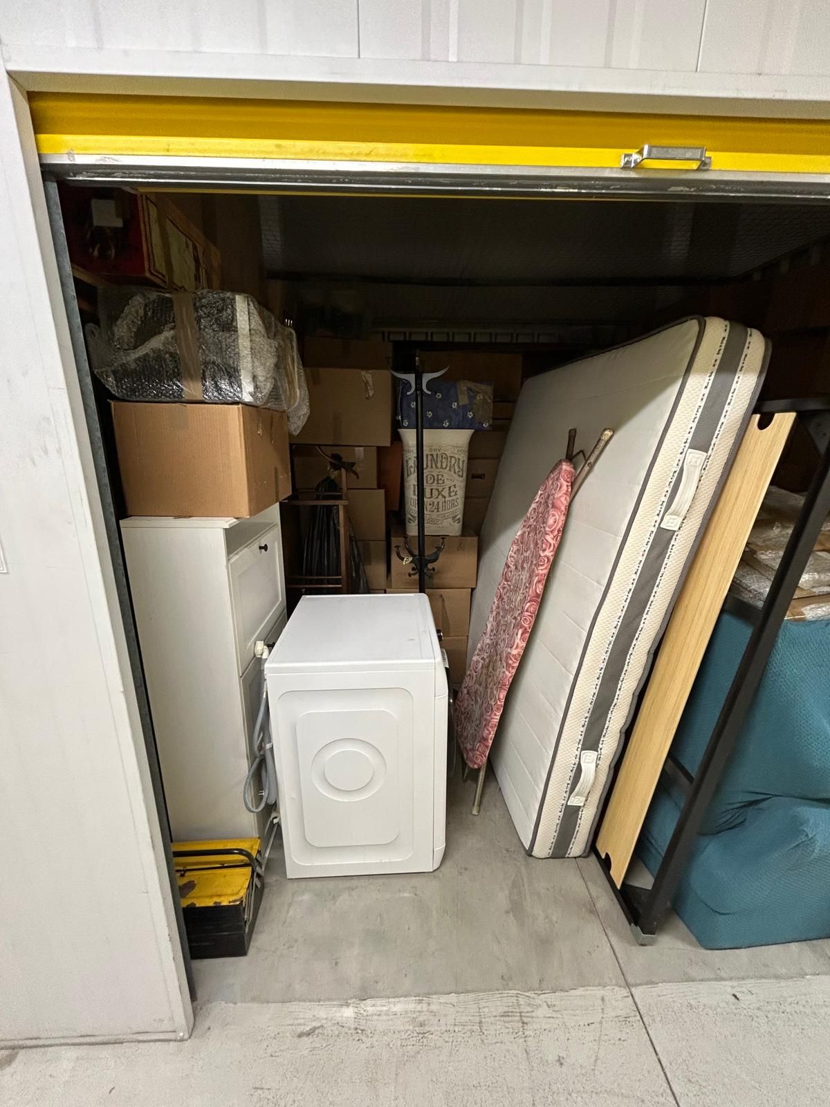 Un magazzino pieno di mobili, scatole e una lavatrice.