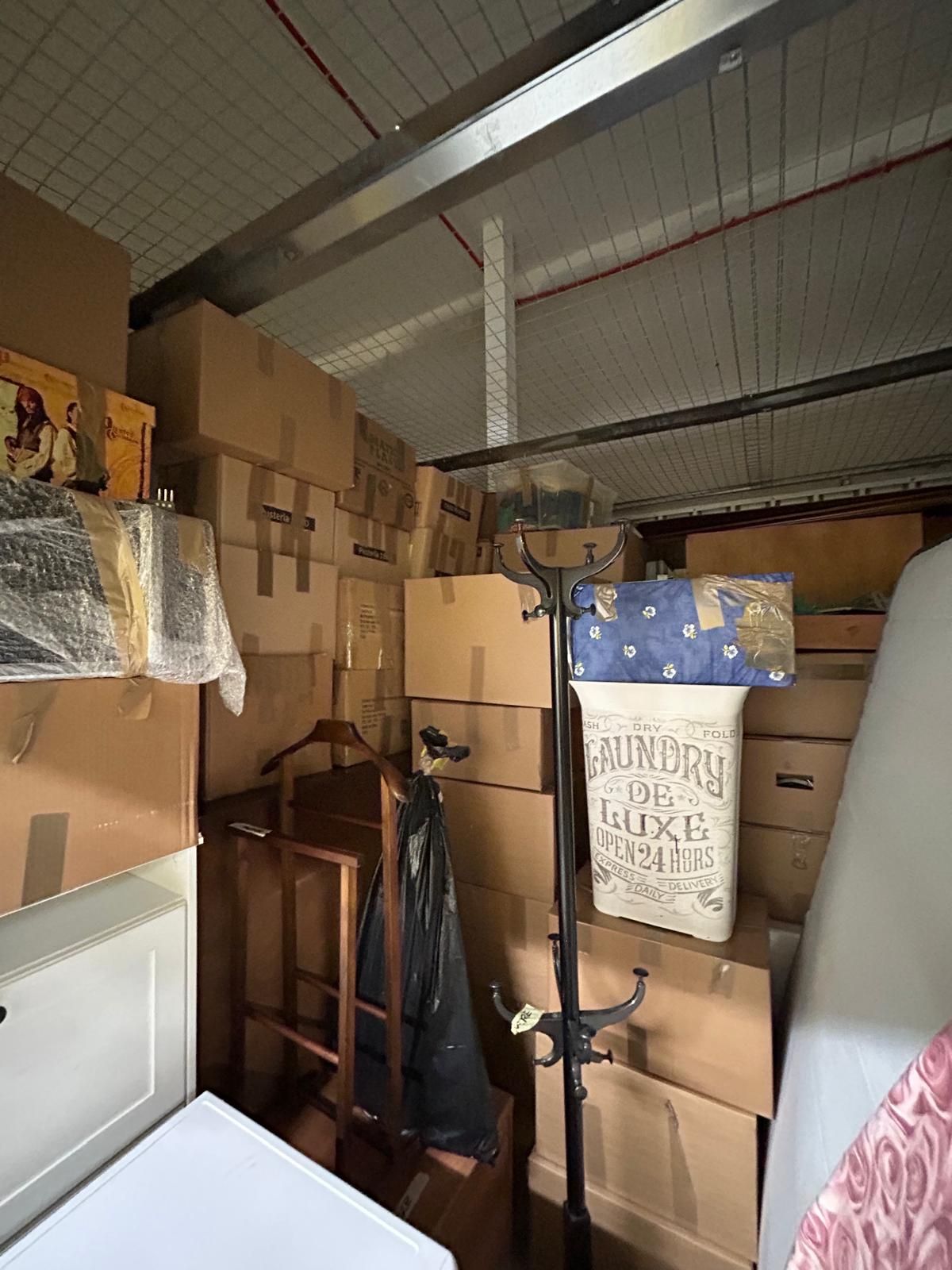 Mobiletto pieno di scatole, mobili e un attaccapanni; spazio disordinato e chiuso.