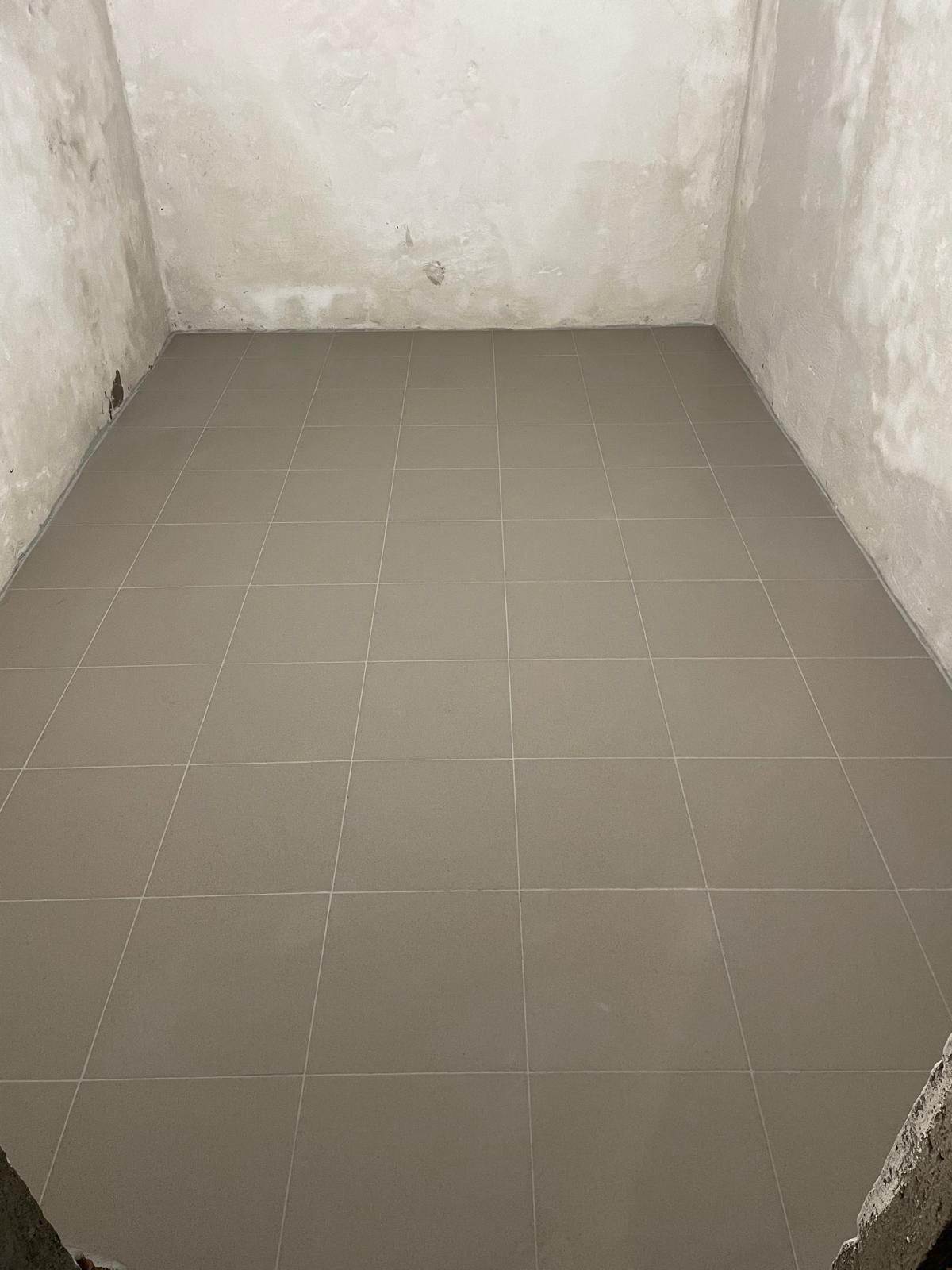 Stanza con pavimento piastrellato grigio, pareti grigie.