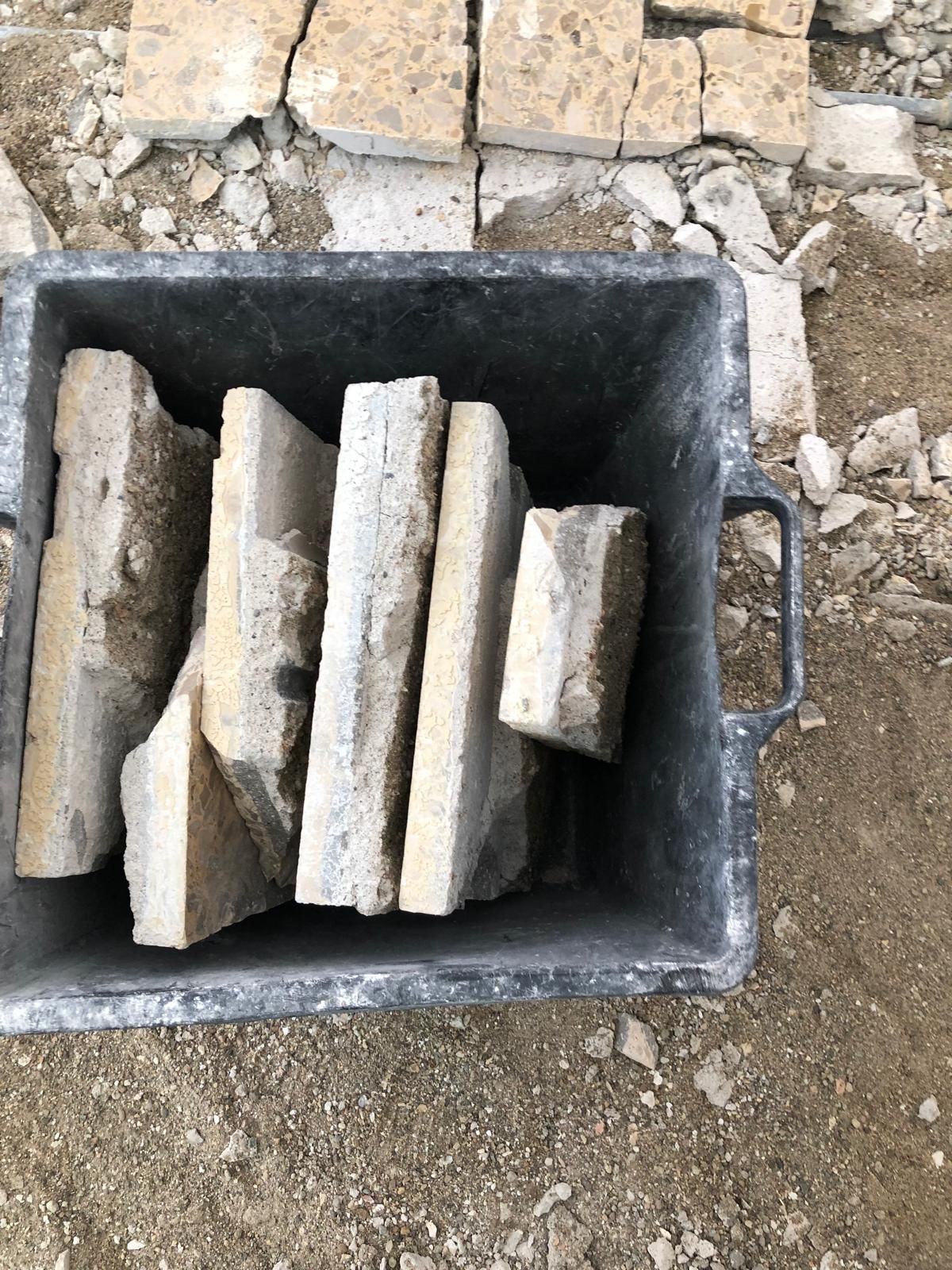 Lastre di pietra in un bidone grigio in un cantiere edile.