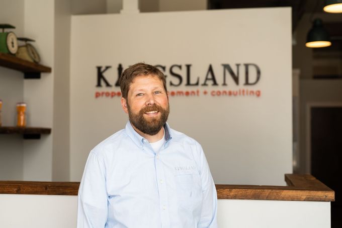 Man standing inside Kingsland office with logo in the background