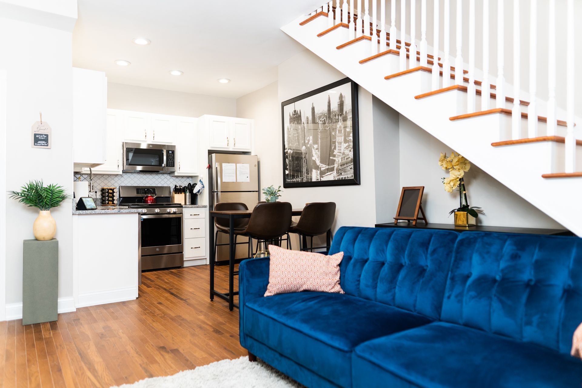 Modern living room and kitchen area with blue couch and staircase