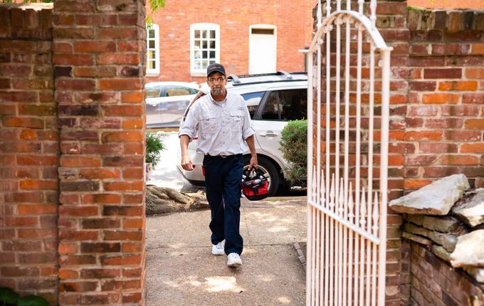 Man exiting brick courtyard through iron gate