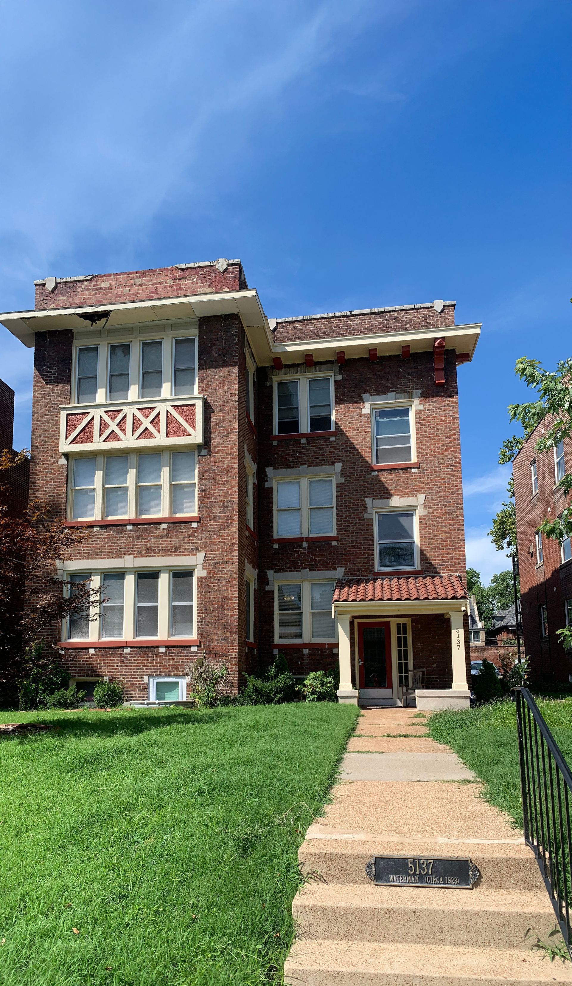 Upward view of a historic triplex building against a blue sky