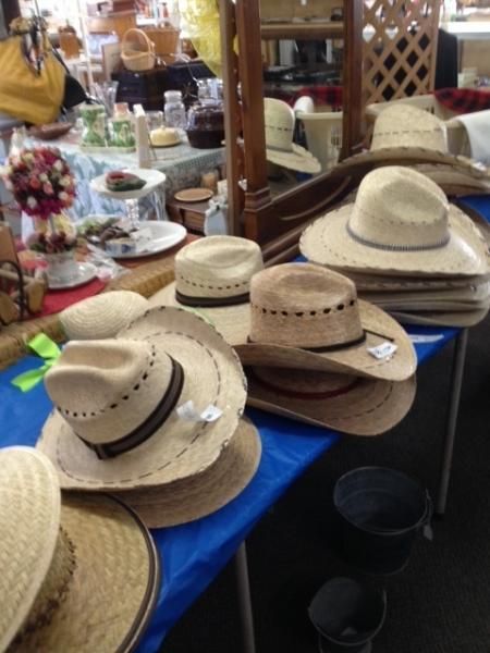 Straw hats with black bands displayed on a market table in an indoor shop.