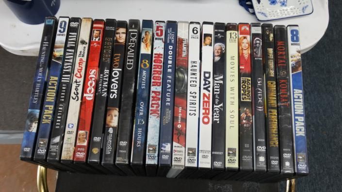 A row of DVD cases lined up on a shelf, with assorted dark and colorful spines visible.