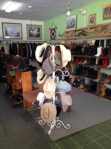 Hat display in a clothing store with racks of apparel and framed wall art