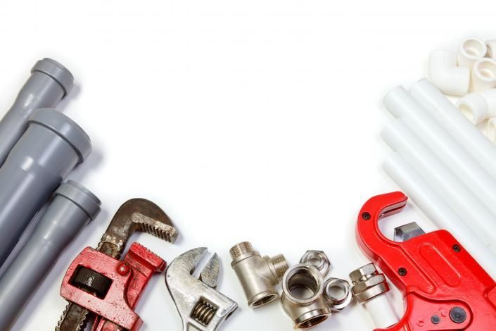 Assorted plumbing tools and pipe fittings on a white background