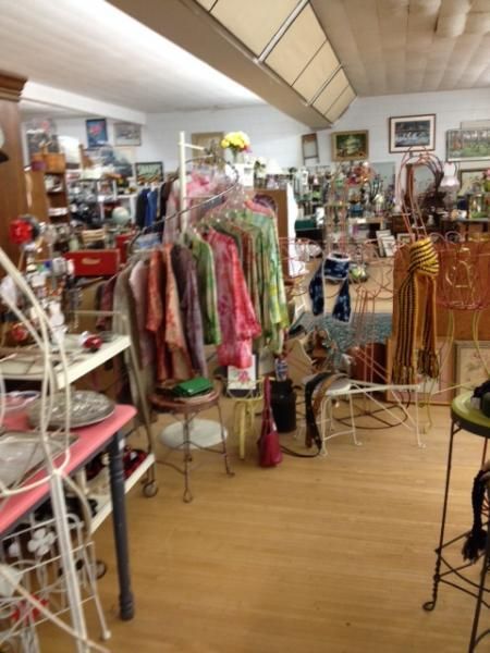 Clothing shop interior with racks of colorful garments, shelves, and decorative items on wooden flooring