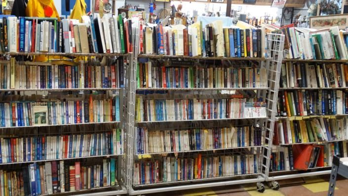 Rows of books on crowded library shelves with colorful spines and a few tilted volumes