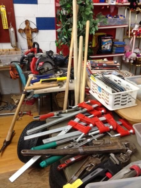 Assorted garden tools and pruning shears piled on a table in a workshop-like room