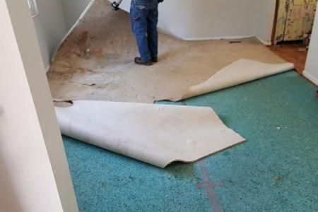A man is laying carpet on the floor in a room.